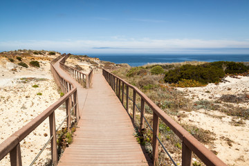 Fototapeta na wymiar Fishermen's route in the Alentejo, promenade with cliffs in Portugal. Wooden walkway along the coastline.