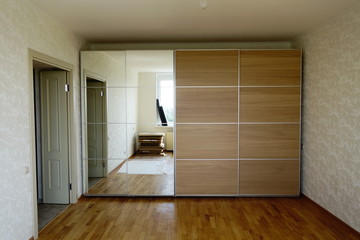 Flat pack furniture wardrobe with a mirror installed wall to wall in a small apartment room
