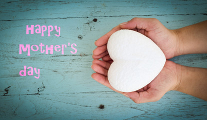 Hand holding white painted hearts on a blue wooden background. Happy Mothers Day