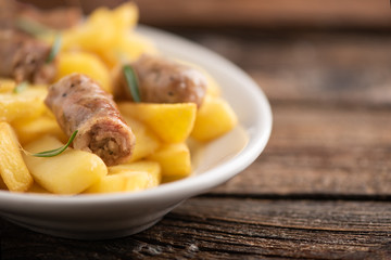 White plate of  italian sausage and potatoes