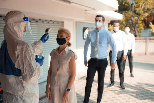 Officer wearing a respirator mask to use infrared forehead thermometer to check fever body temperature for virus symptoms. Respiratory diseases such as flu, covid19, coronavirus. Epidemic outbreak