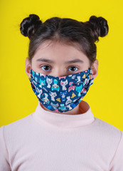 Little cute girl with colorful  mask on yellow background. Stay home. Stop covid-19. Dispasoble mask. Virus protection equipment. Quarantine. Girl plays a doctor. education and occupation concept