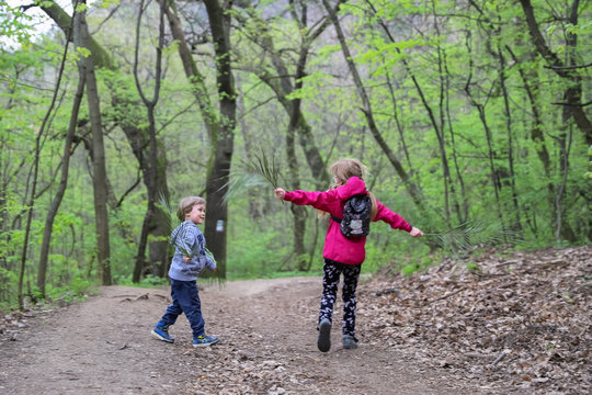 Boy and girl playing as fly through the forest in early spring