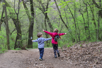 Boy and girl playing as fly through the forest in early spring