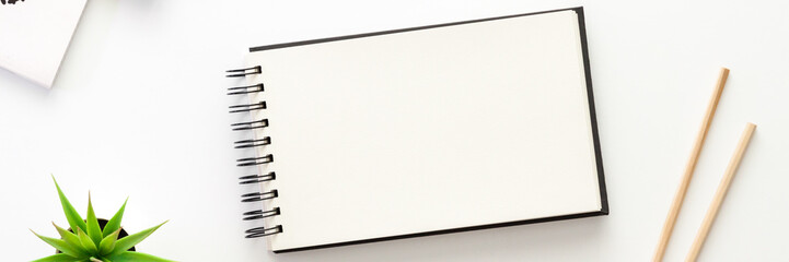 A white desk with an open sketchbook. Mockup. Panorama