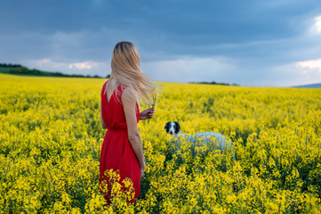 Naklejka na ściany i meble Woman with Russian wolfhound dog in rapeseed field
