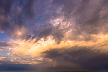 Sunset and dramatic set of clouds drifting over the tropical waters of the Caribbean Sea are lit by the last moments of daylight.