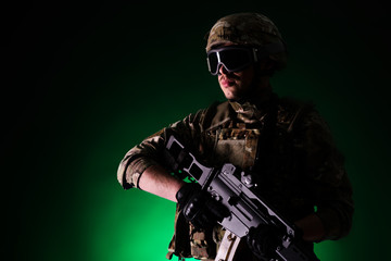 Soldier with gun is on mission on green background. Concept of war.