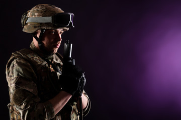 Fototapeta premium Soldier with gun aims at the target on mission on violet background. Concept of war.