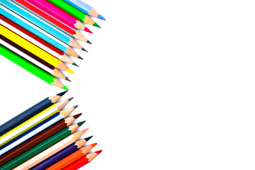 Different colored wood pencil crayons pointing at a empty space on a white paper
