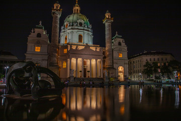 Fototapeta na wymiar An evening gathering for both locals and tourists at the reflecting pool outside of St. Charles Church in Vienna, Austria