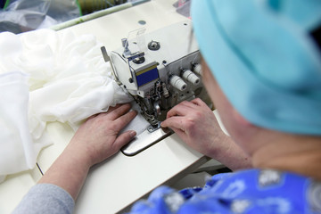 A woman sews gauze bandages on a sewing machine.