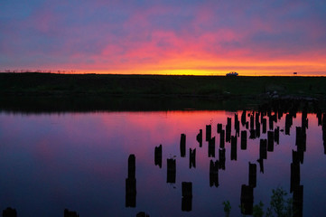Beautiful violet-blue sunset on a small river wooden posts in the water