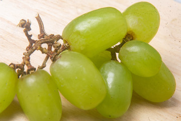 A branch of green grapes on a wooden background