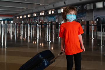 Fototapeta na wymiar A child in a protective mask at the airport. Traveling during the Covid 19 coronaviruse. Social lockdown in US, America. Social distancing, stay safe to beat corona viruses. Quarantine and flight ban.