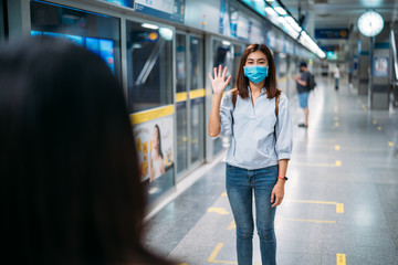 Two young asian women friends wearing protective mask meet in a subway station with bare hands. Instead of greeting with a hug or handshake due to Coronavirus disease or COVID-19 outbreak situation
