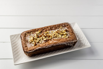 Banana loaf cake with nuts on top wooden table top view.