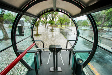 Fototapeta premium Típico ponto de ônibus de Curitiba. Estação circular de vidro em dia chuvoso.