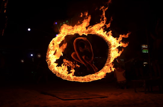 Mężczyzna skaczący przez ognisty krąg  podczas full moon party na wyspie Phi Phi w Tajlandii