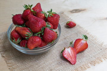 Strawberries in a glass plate on a wooden background. Strawberry season.