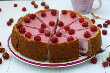 Homemade raspberry cheesecake cut in portions on a plate, located on white background, Horizontal format