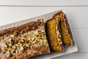 Banana loaf cake with nuts on top cut open wooden table top view.