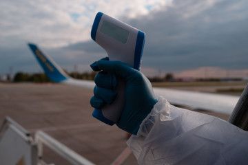 Covid. Measure body temperature at the border and aeroport. Steward in gloves holds a thermometer...
