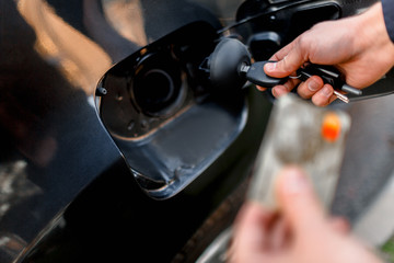 Man with credit card opening fuel tank of his new car. Cashless calculation of money. Fuel, oil gasoline, diesel, gas concept