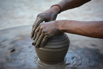 Hands working on pottery wheel and making a pot