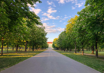 An empty street across a green park in Vienna.