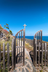 Cliff way around Kolymvaria, Greece. The narrow path winds along the steep cliffs. A gate allows...