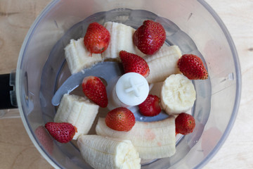 Banana and strawberries in a blender bowl are ready to mix. Tasty drink. Yummy.