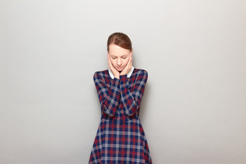 Portrait of unhappy young woman touching cheeks with hands