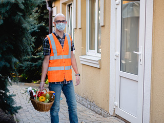 A male volunteer in a medical mask delivers food to people who are self-isolated during quarantine.