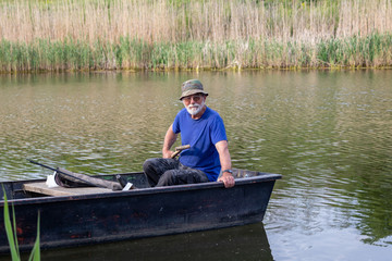 Senior fisherman in a boat at Danube-Tisa-Danube channel near Novi Sad, Serbia.