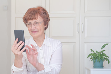 Senior woman using mobile phone at home. Happy retired person shopping online.