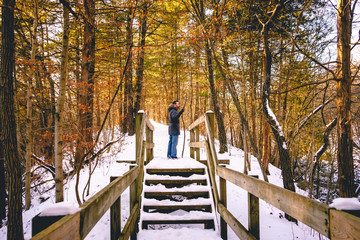 A young caucasian man centered in a snow covered orange colored forest in Matthiessen State Park near Chicago, Illinois, USA. - Powered by Adobe