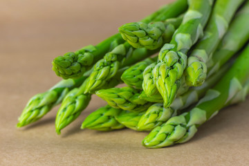 Bunch of fresh asparagus close-up. Selective focus, brown blurred background.
