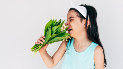 Image of joyful child holds the bunch of white flowers for her mother. Cute kid laughing and holds a bouquet, isolated on white background. Pretty toddler girl prepared a gift the bouquet for mom.