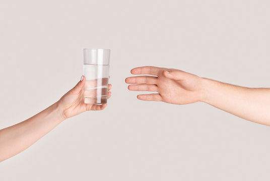 Young Girl Giving Glass Of Fresh Clear Water To Man On Light Background, Closeup Of Hands. Panorama