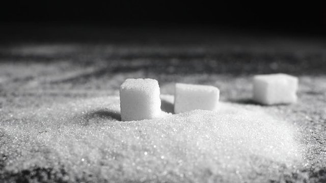 Refined sugar cubes falls on sugar sand. slow motion, inversion