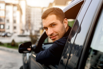 A well-looking man looks from his car and looks back. The driver is in a residential area of the...