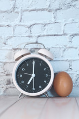alarm clock and egg on table with copy space.