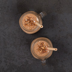 Smoothies from dried fruits, prunes, raisins, nuts in a jar with bamboo straws on a dark background top view