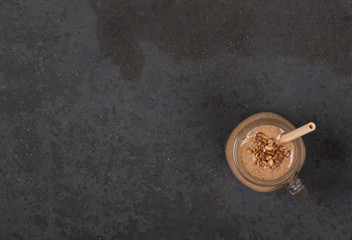 Energy drink smoothie from dried fruits, prunes, raisins, nuts in a jar with bamboo straws on a dark background top view