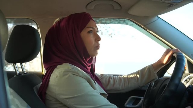 An emancipated modern Muslim woman in a hijab drives a car