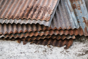 Sharp edges of the rusty metal sheets placed on the floor. Old aged weathered rusty galvanized corrugated iron sheet roof of abandoned mood. selective focus blur background. Vintage.