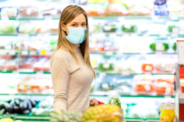 Woman shopping in a supermarket wearing a mask - coronavirus concept