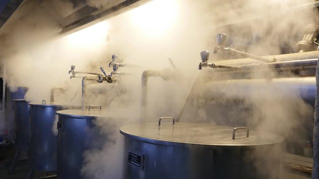 Steam billows from large metal pots