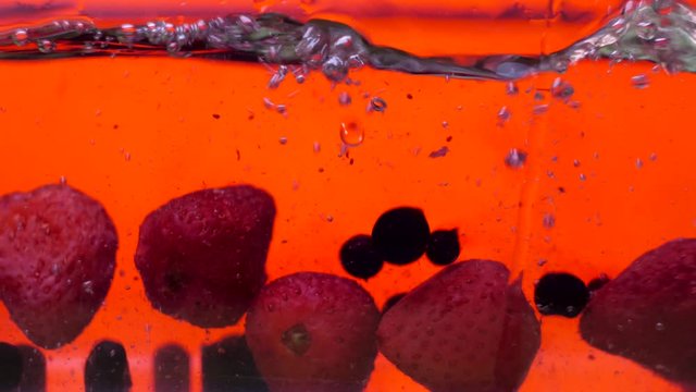 Strawberries and blueberries falling into the water container